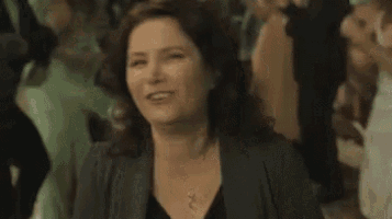 a woman is sitting in a crowd of people and smiling .