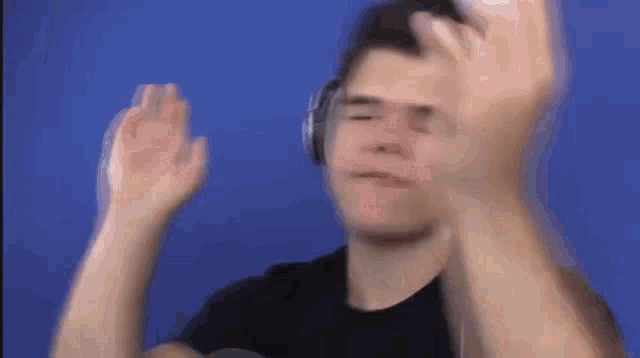 a man wearing headphones is making a funny face while holding his hands up in the air .