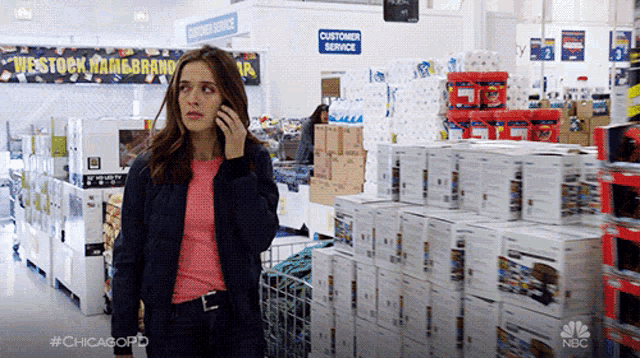 a woman talking on a cell phone in a store with a customer service sign behind her