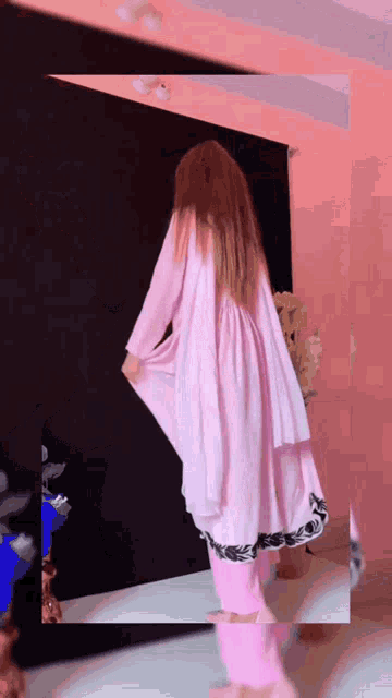 a woman in a pink dress is standing in a room