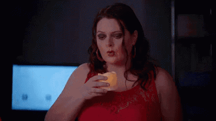 a woman in a red dress is holding a candle in her hand .