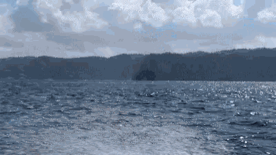 a large body of water with mountains in the background and a cloudy sky