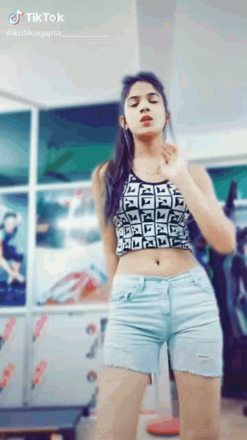 a girl in a crop top and shorts is dancing on tiktok