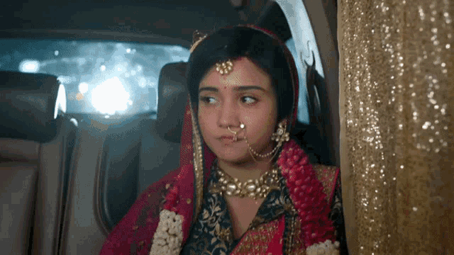 a woman with a nose ring is sitting in the back of a car
