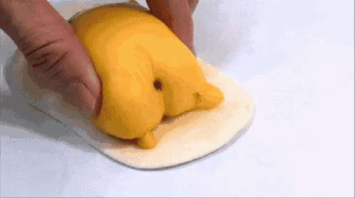 a person is holding a yellow object that looks like a chicken butt