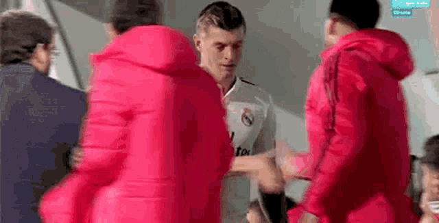 a group of people are standing around a man in a red jacket .