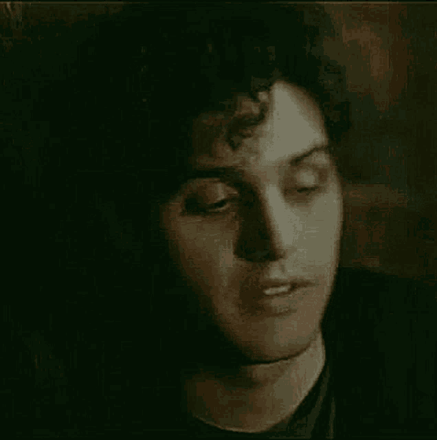 a close up of a man 's face with his eyes closed and a black shirt on .