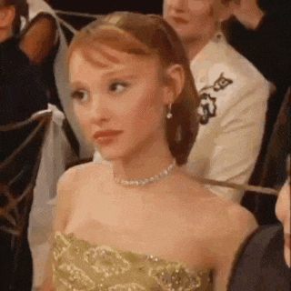 a woman in a strapless dress and a choker is sitting in a crowd of people .