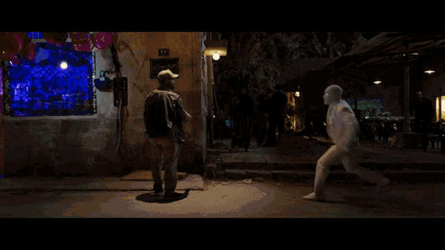 a man in a white suit is fighting another man in front of a store with a sign that says 17 on it