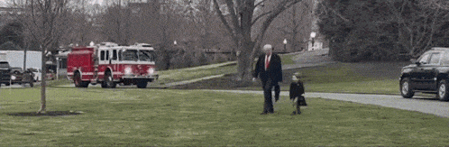 a man and a child walking in front of a fire truck .