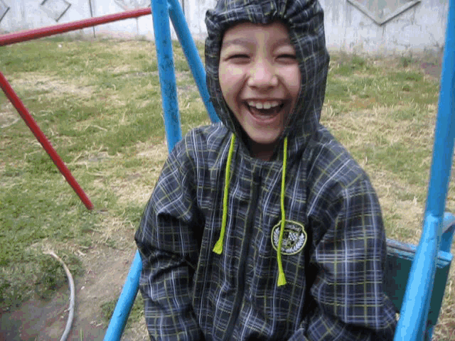 a young boy wearing a plaid jacket with the word columbia on the front is smiling