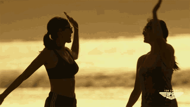 two women standing on a beach with the words top gun america on the bottom right