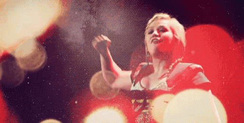 a woman is singing into a microphone in front of a red background