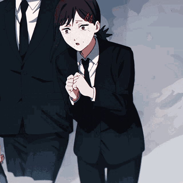 a man in a suit and tie stands next to a girl in a suit
