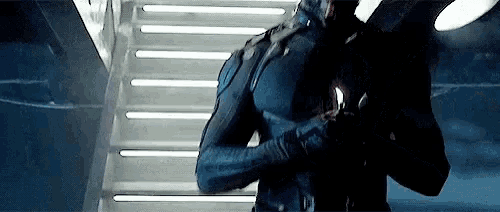 a man in a black suit is standing on a set of stairs with his arms crossed .