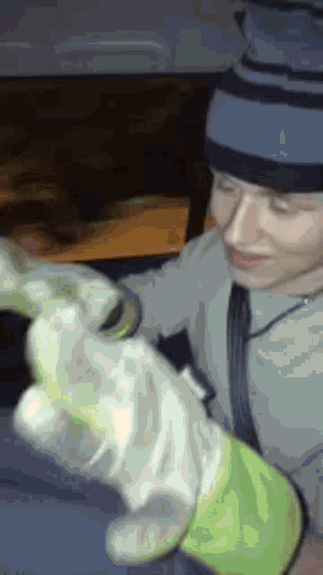 a man wearing a hat and gloves is holding a green object in his hands .