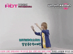 a man in a blue jacket is dancing in front of a wall that says hot