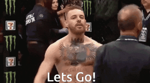 a man with a tattoo on his chest is standing next to a man and says let 's go