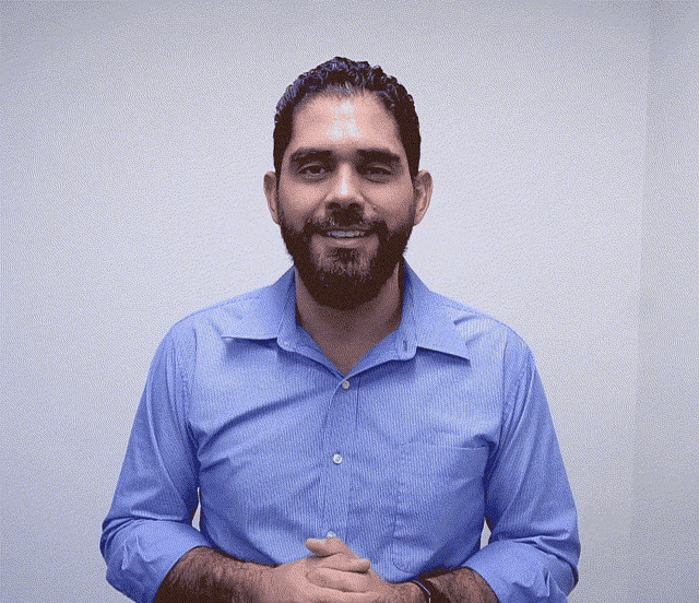a man with a beard wearing a blue shirt is smiling