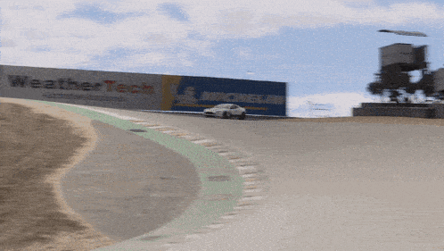 a car is driving down a race track with a sign that says weather tech on it