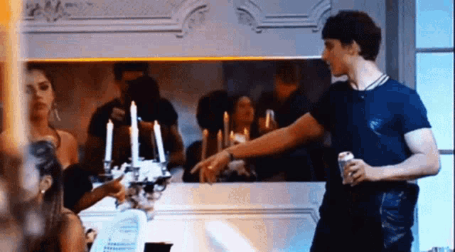 a man in a blue shirt is standing in front of a mirror with candles on it