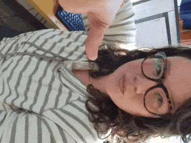 a woman wearing glasses is giving a thumbs up