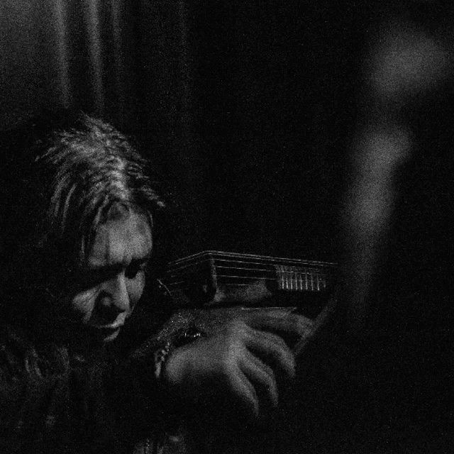 a woman playing a violin in a dark room