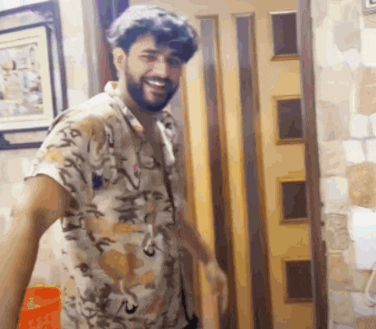a man with a beard is standing in front of a door smiling .