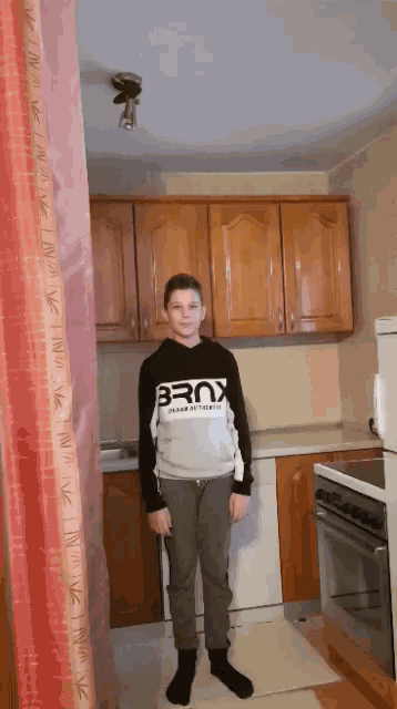 a boy in a kitchen wearing a shirt that says bronx
