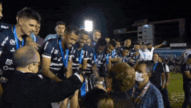 a group of soccer players are celebrating a victory with a man in a mask