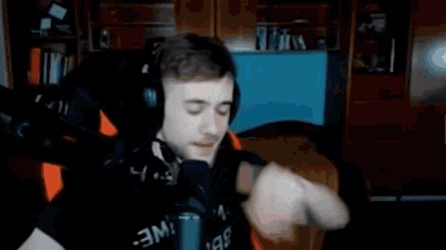 a man wearing headphones and a black shirt is giving a thumbs up .