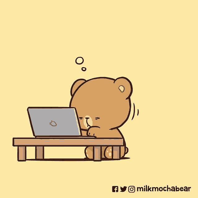 a teddy bear is sitting at a table using a laptop computer