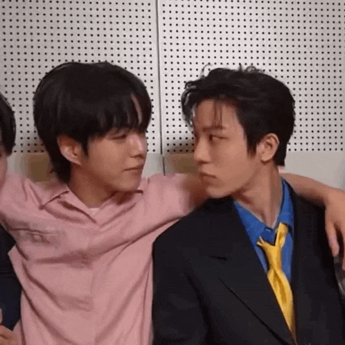two men are sitting next to each other and looking at each other .