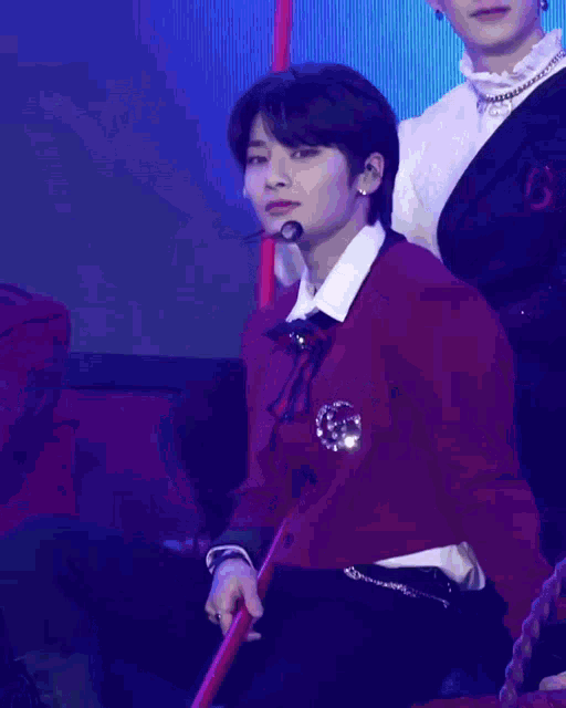 a young man in a red sweater is holding a red stick in his hand .