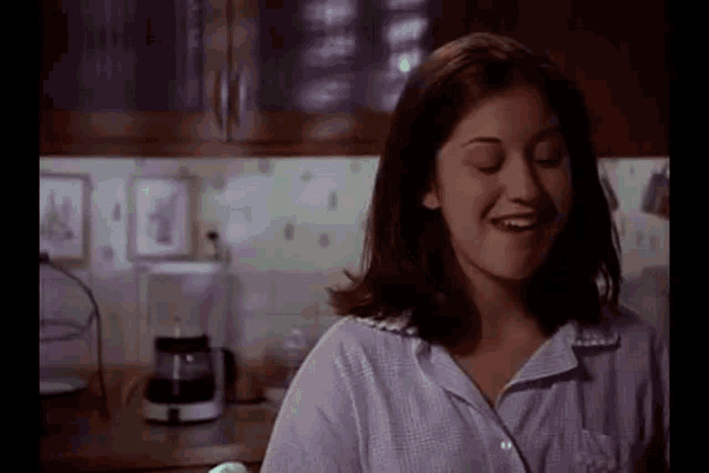 a woman is sitting in a kitchen with her eyes closed .