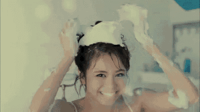a woman is taking a bath with soap foam on her head .