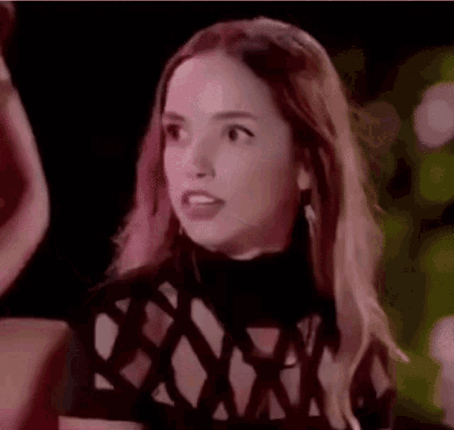 a woman in a black dress is making a funny face while standing in front of a group of people .