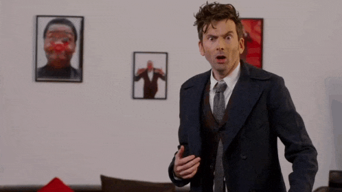 a man in a suit and tie is screaming in a living room with the word aaah behind him .