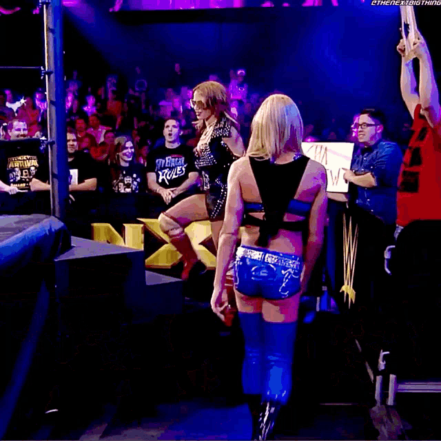 a woman stands in a wrestling ring with a sign that says oss on it