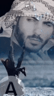 a man with a beard is wearing a head scarf and holding a sword in his hand .