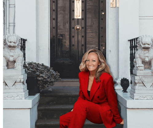 a woman in a red suit sits on steps in front of a door