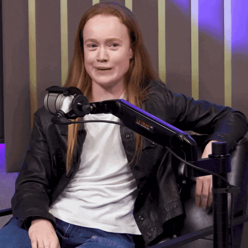 a woman in a leather jacket sits in front of a microphone that says ultra on it