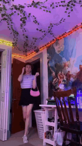 a woman is dancing in a room with purple lights on the ceiling and a painting on the wall .