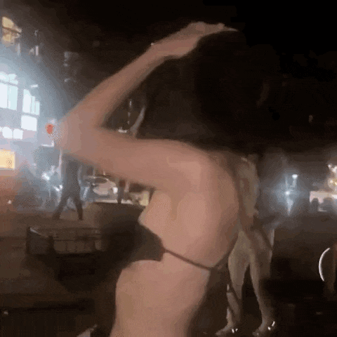 a woman in a bikini is dancing in front of a crowd of people .