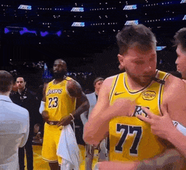 a basketball player with the number 77 on his jersey is standing next to a basketball player with the number 23 on his jersey .