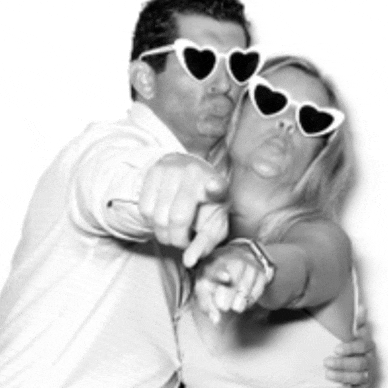 a man and a woman wearing heart shaped sunglasses are pointing at the camera