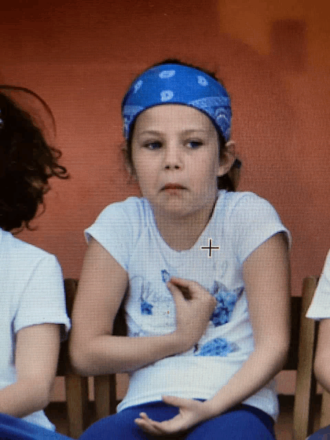 a little girl wearing a blue headband with a cross on it