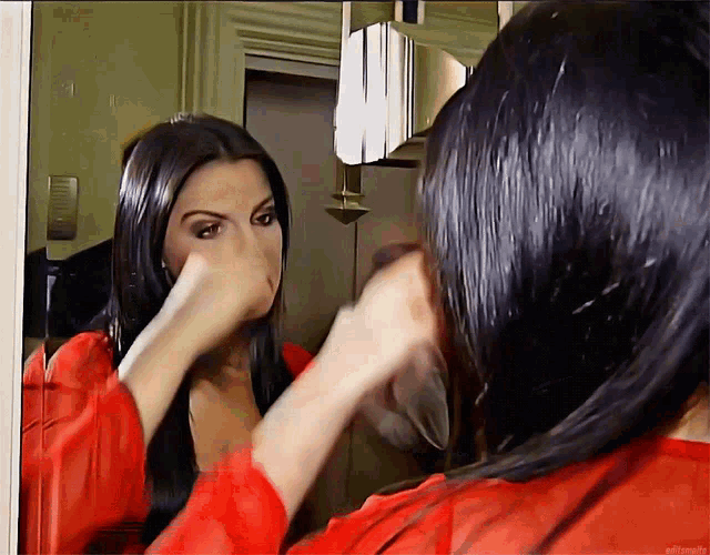 a woman in a red dress looks at herself in the mirror
