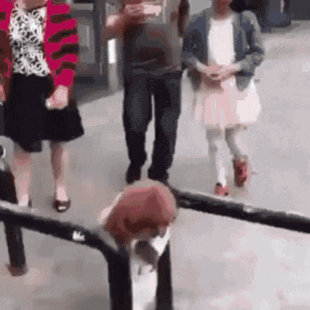 a group of people are walking down a sidewalk next to a fence .