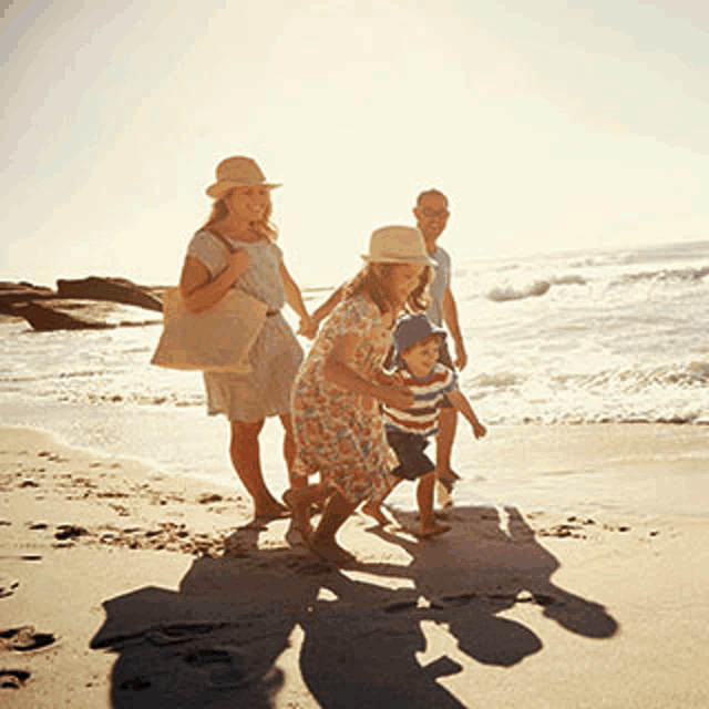 a family is walking along the beach holding hands .